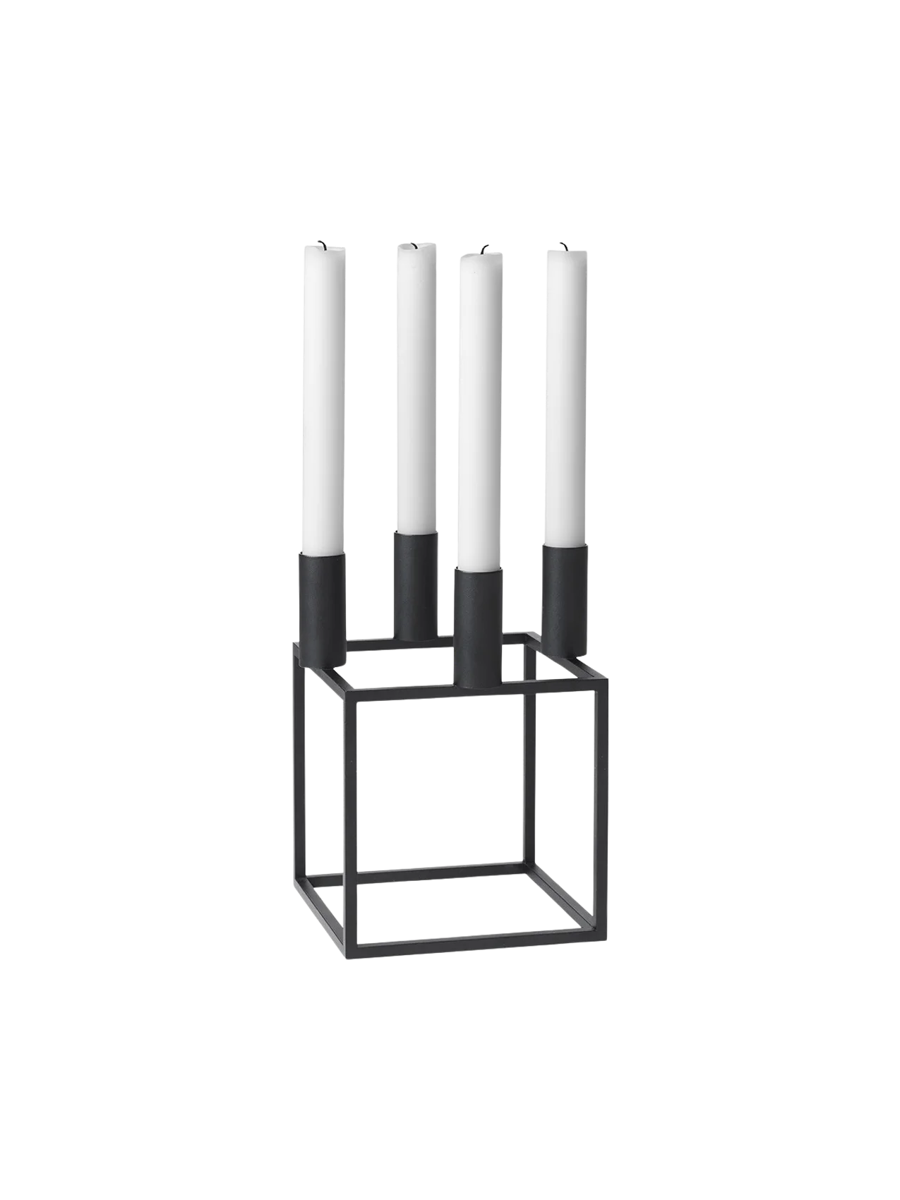 A black, geometric Kubus 4 candle holder with a square base, holding four tall white unlit candles, on a black background.