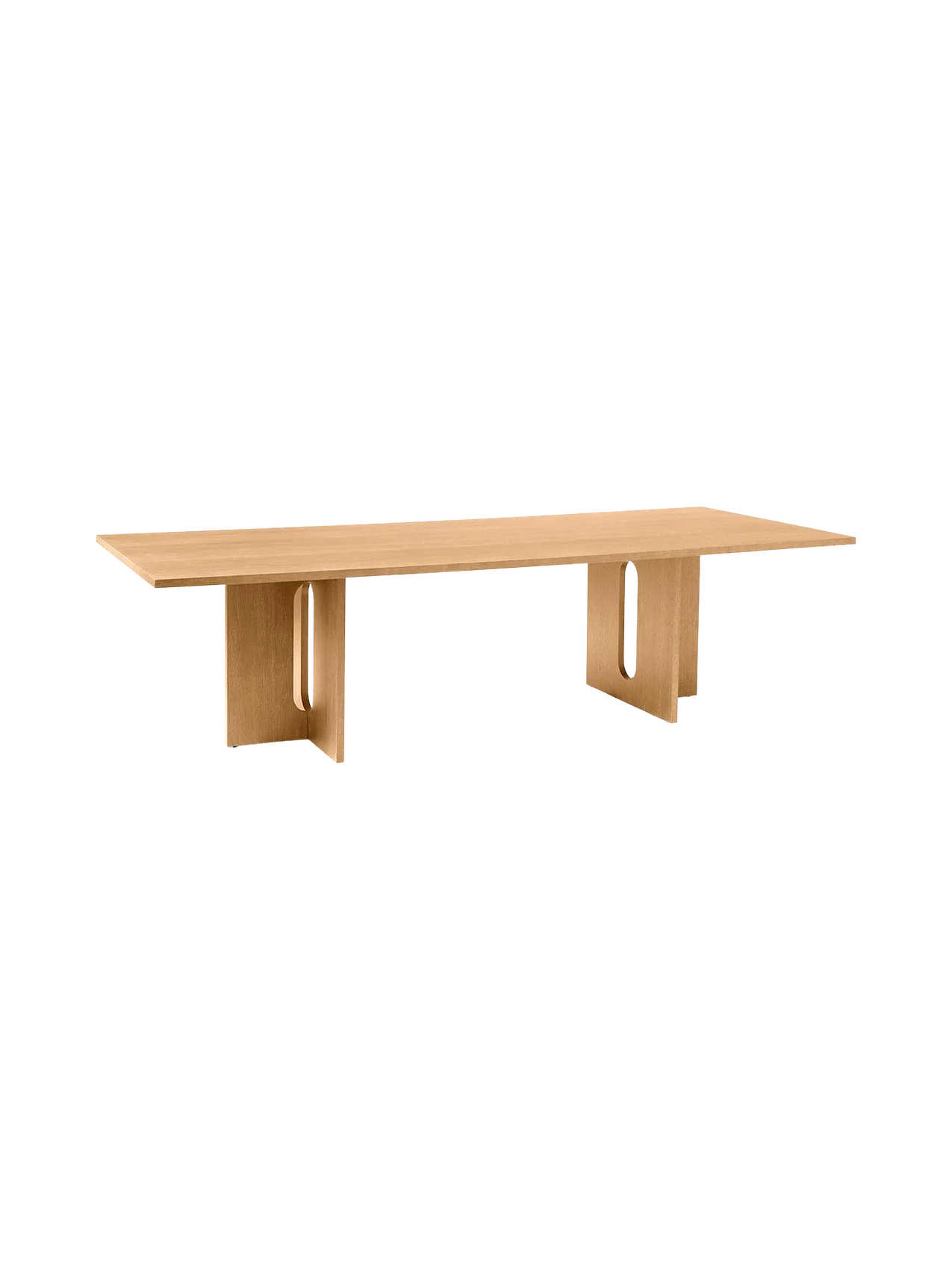 Angled view of the long, rectangular Androgyne Dining Table in natural oak, featuring two wide legs with oblong cutouts.