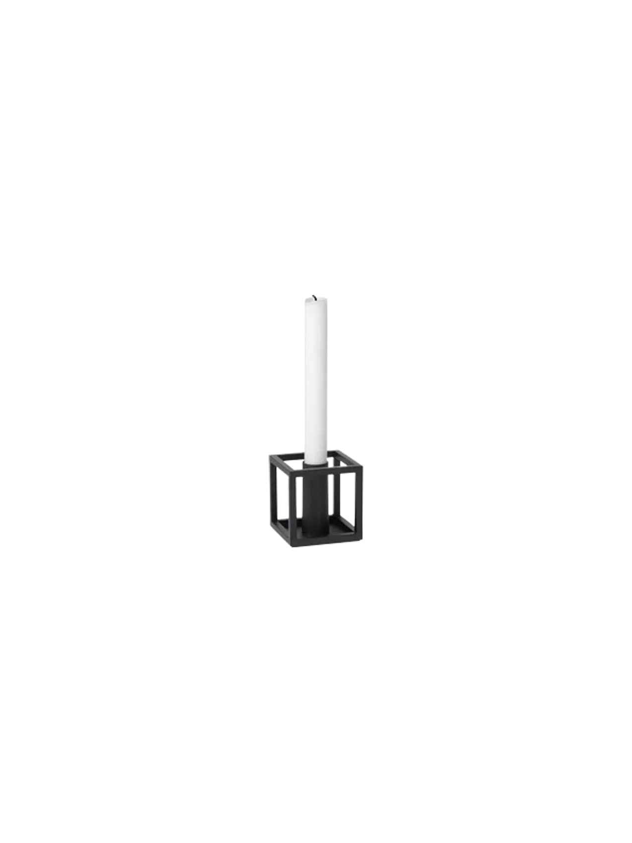 The Kubus 1 candle holder in black, a cube-shaped metal frame holding a single tall white candle against a black background.