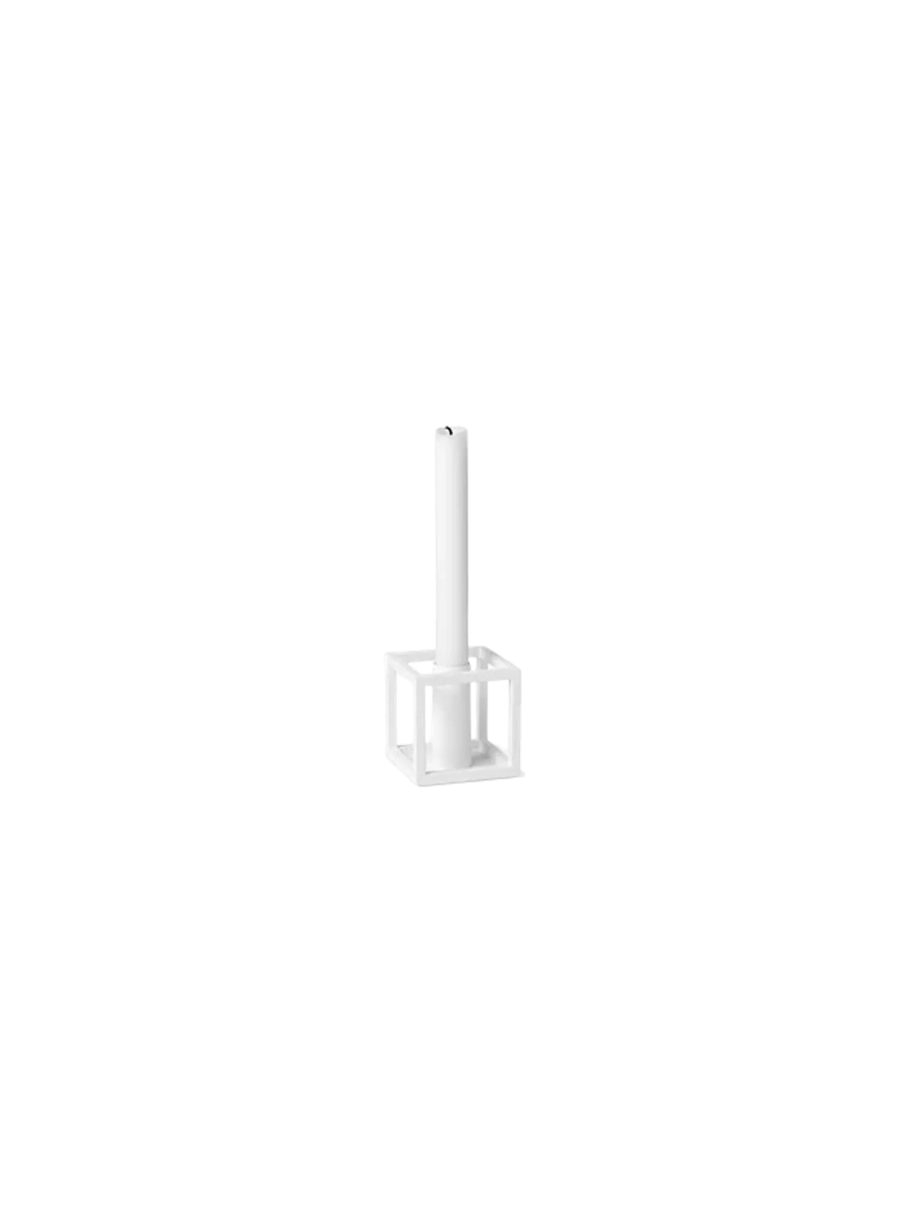 A white Kubus 1 candlestick holder, with its geometric cube design, holding a single white candle against a black background.