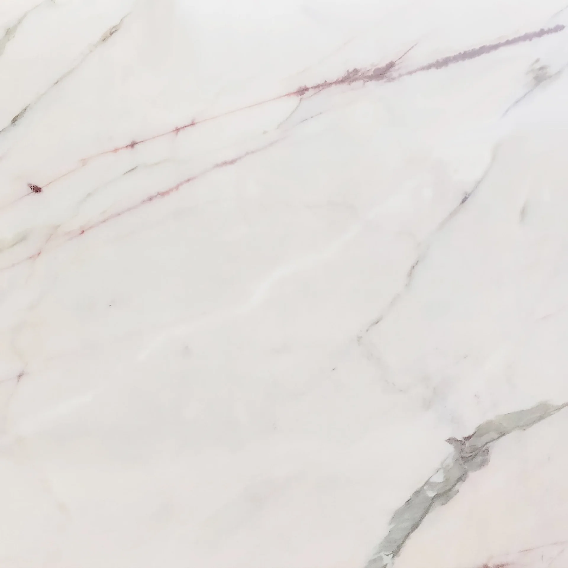 A close-up view of an Estremoz marble slab, showcasing its white base with delicate, diagonal veins of grey and mauve.