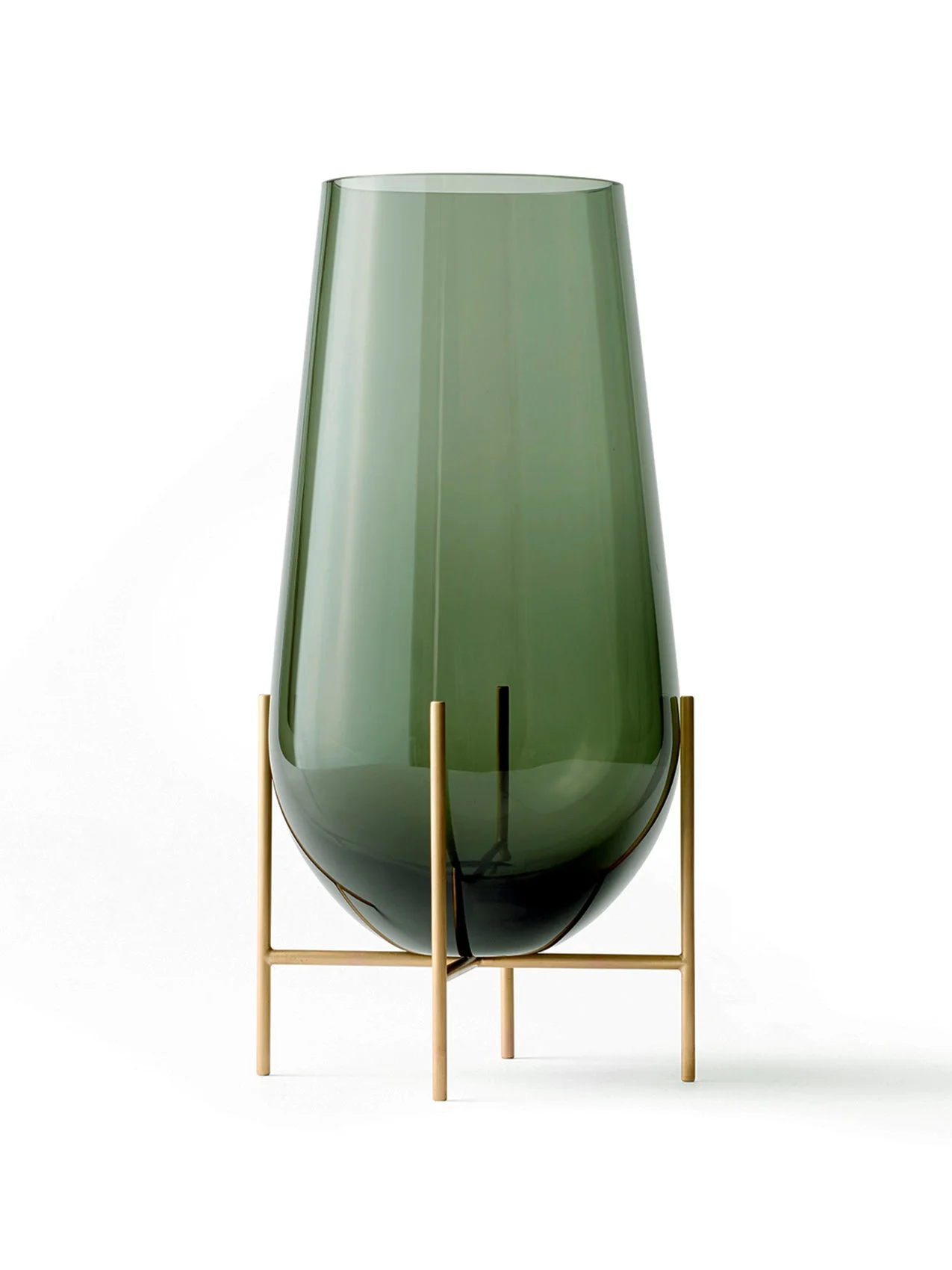A large Echasse Vase in smoked green glass, resting in a slender brushed brass stand against a white background.