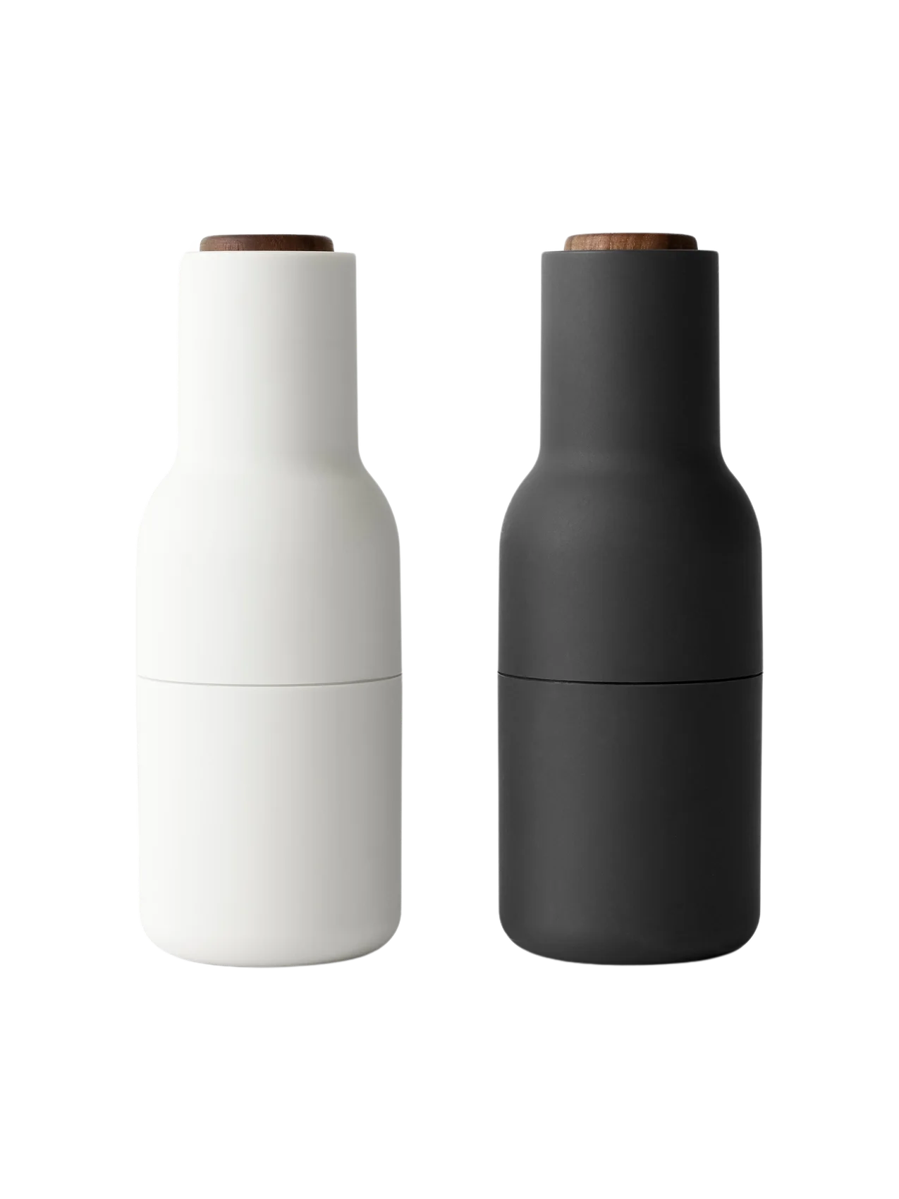 Front view of the Audo Bottle Grinder set in Ash and Carbon. The minimalist grinders feature a matte finish and walnut lids.