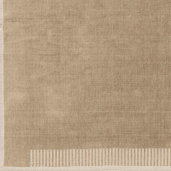 A close-up detail of the corner of the Duomo Rug in Limestone Beige, highlighting its woven texture and striped border.