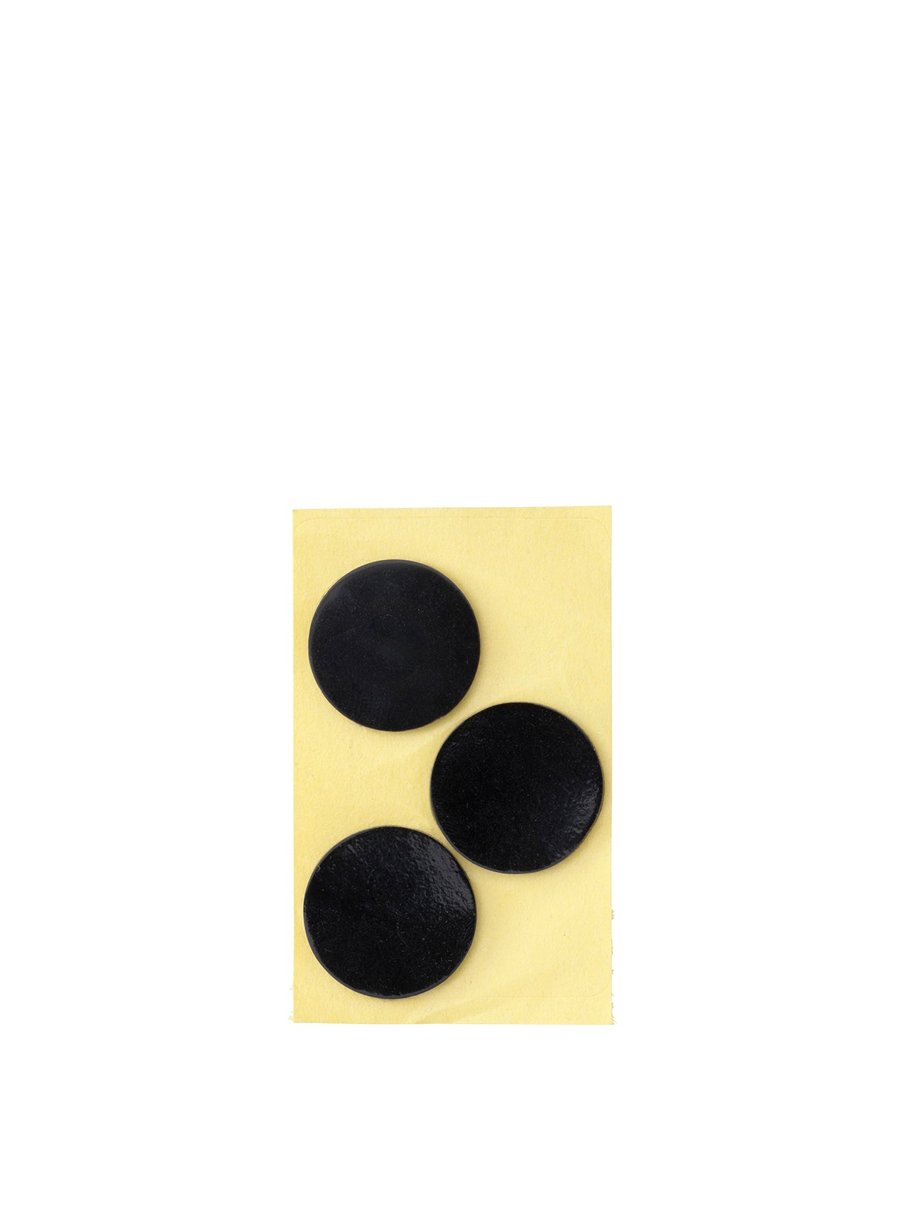 Three round, black silicone feet for the JWDA Lamp, shown on their yellow adhesive backing against a white background.