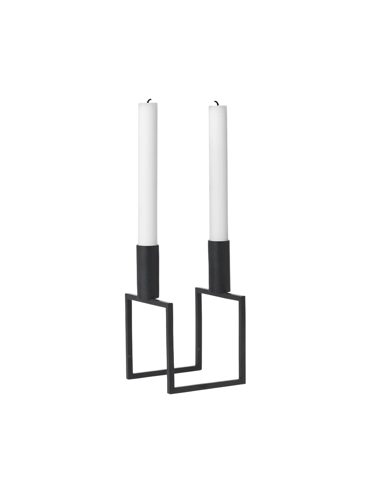 A black, geometric Kubus Line candle holder with two tall white candles, viewed from an angle against a black background.
