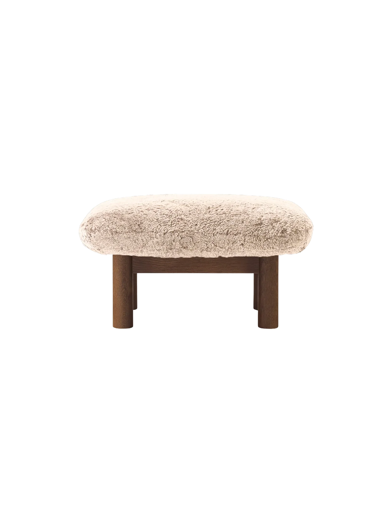 The Brasilia Ottoman with a plush Sheepskin Root cushion on a dark-stained oak frame and four robust legs.