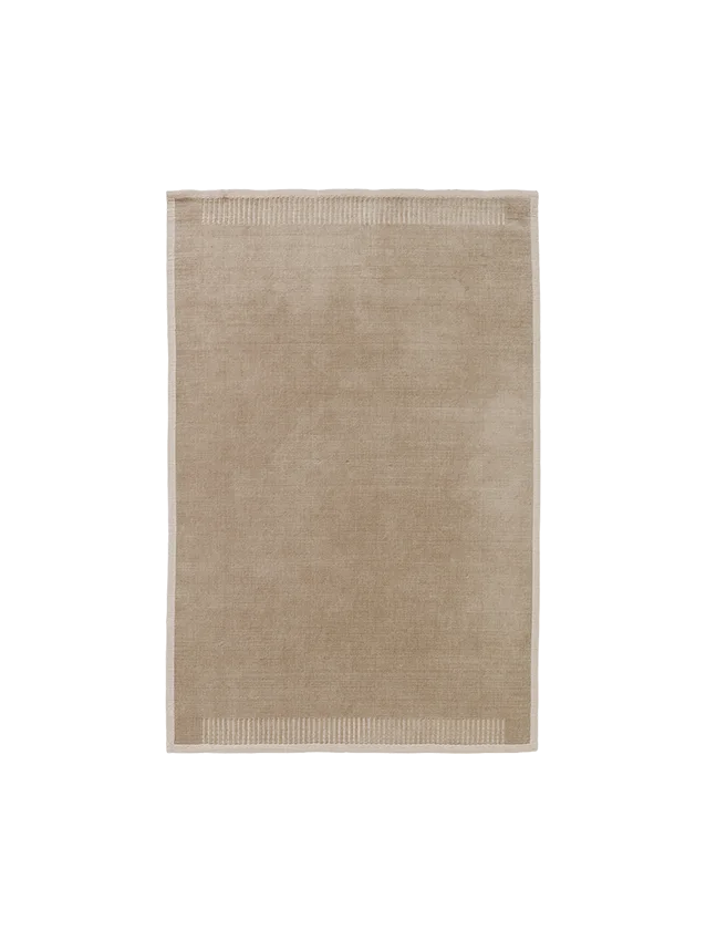 A top-down view of the rectangular Duomo Rug in Limestone Beige, showing a solid-coloured body and decorative ribbed borders.