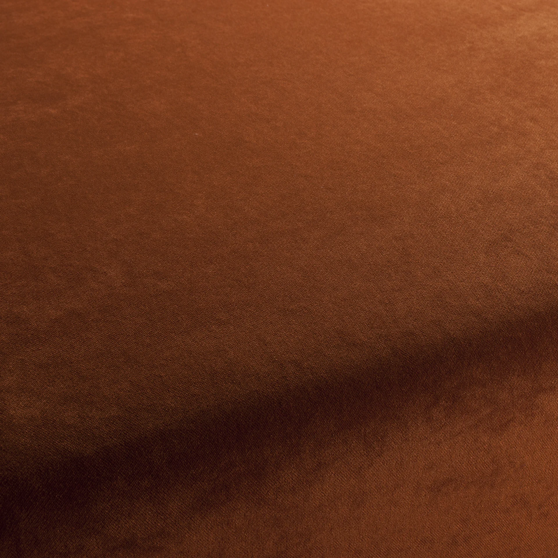 Close-up of warm rust-brown velvet fabric with soft pile and subtle texture.