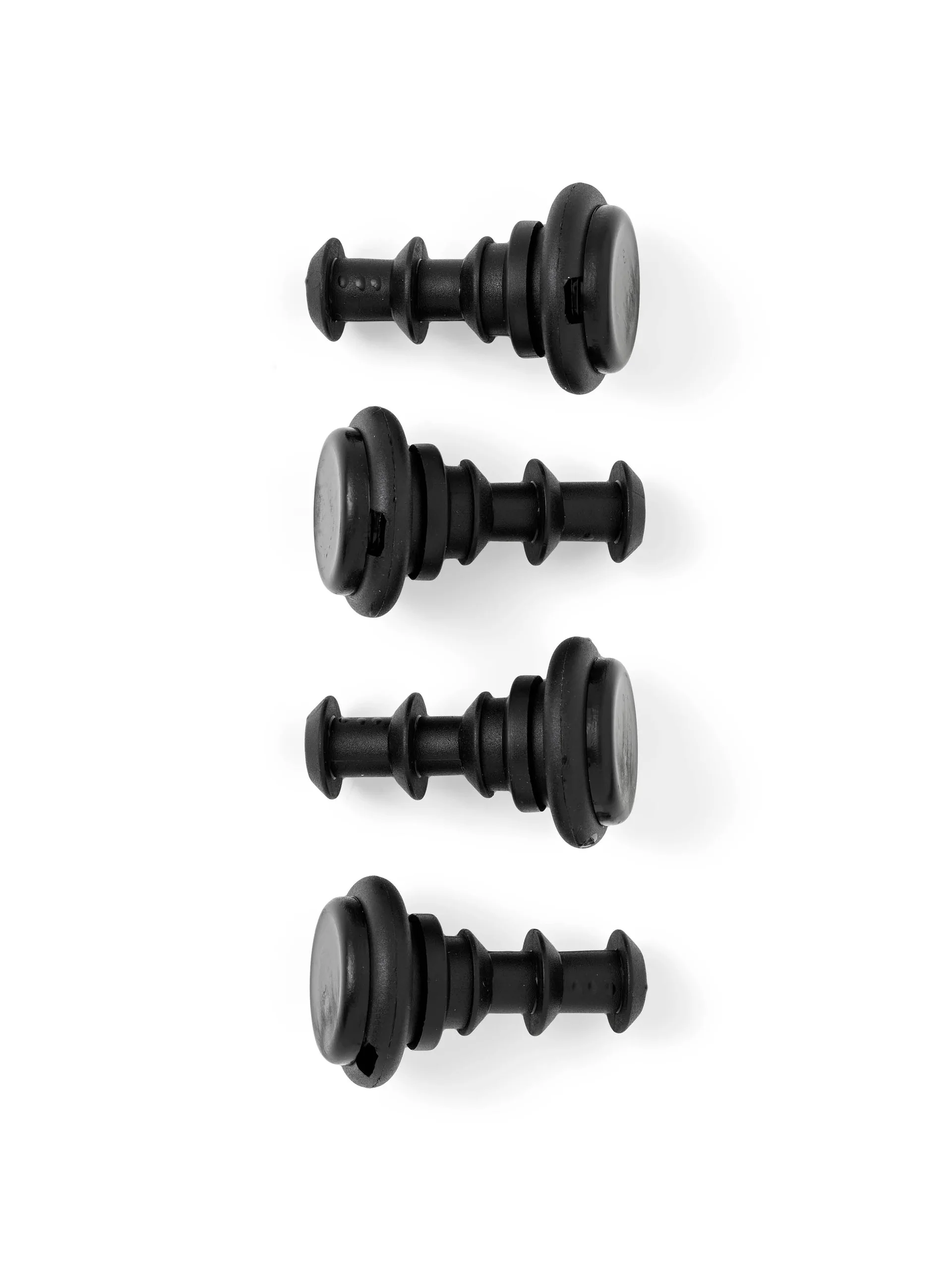 Overhead view of four black, ribbed rubber plugs for the Passage Stool, lined up on a white background.
