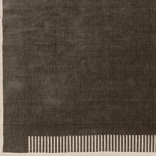 A close-up of the Duomo Rug in Marble Grey, showing the dark grey textured pile and the cream border with a striped pattern.
