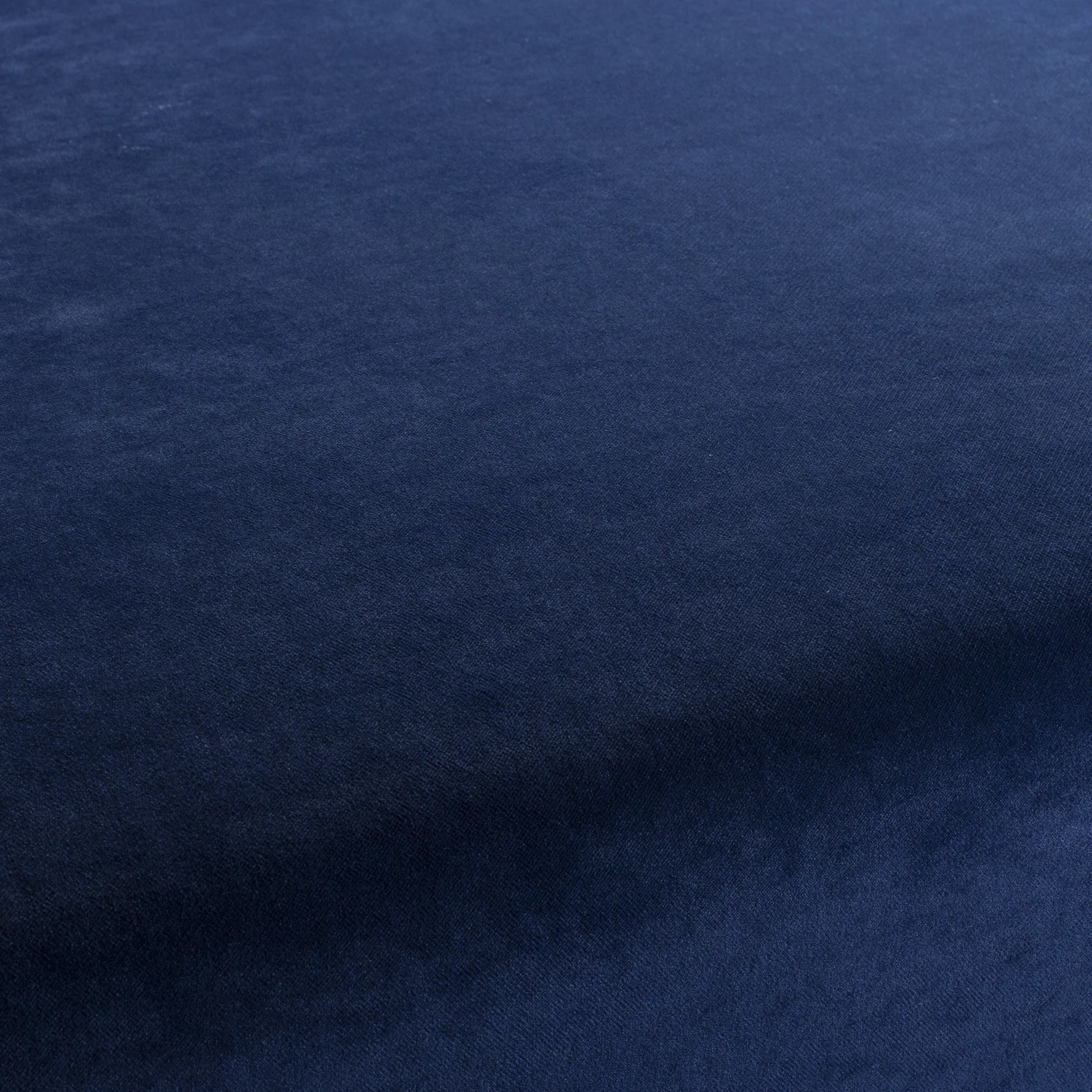 Close-up of deep navy velvet fabric with soft, slightly textured pile and subtle light sheen